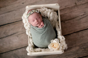 Newborn girl lying in a bed with sage green.