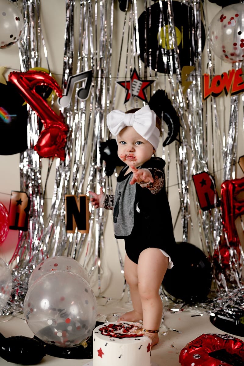 First birthday photo session in studio. Theme of Another ONE bites the dust. Music notes and streamers and balloons in the background.