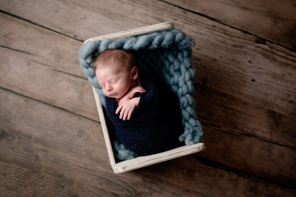 Newborn baby boy in a bed with blue.
