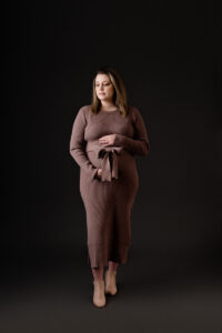 In studio maternity session in Morgantown, WV. Mom is wearing a sweater dress and holding her baby bump. She has on beautiful ankle boots to complement the dress.