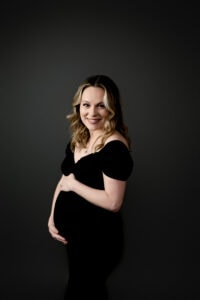 Studio maternity session in Morgantown, WV. Mom is wearing a black dress from the client closet and holding her bump.