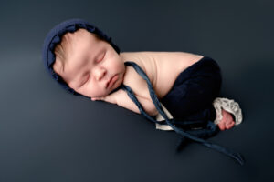 Newborn baby girl in blue lace pants and hat.