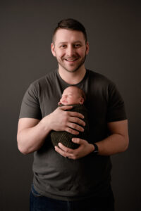 Dad holding newborn son and smiling. Newborn studio in Morgantown, WV.