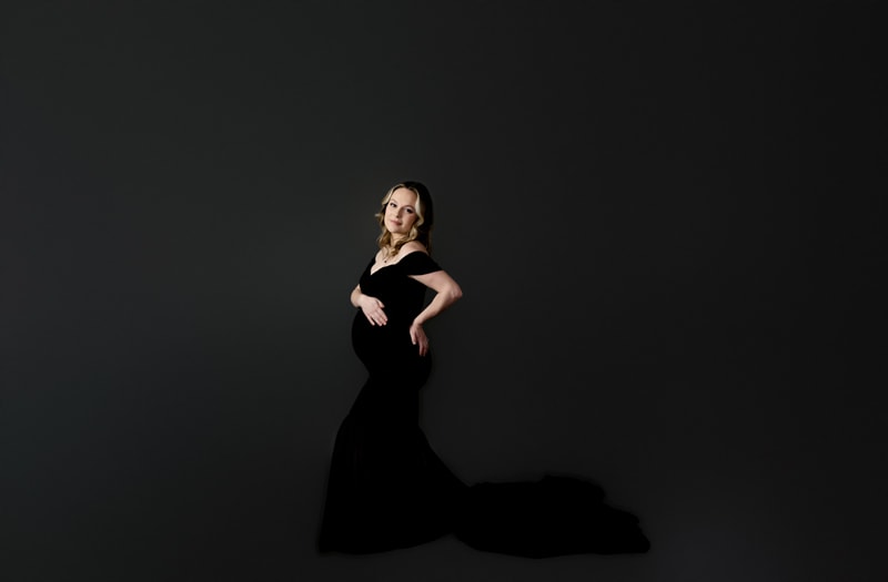 Maternity session in studio, mom is wearing a long black dress.