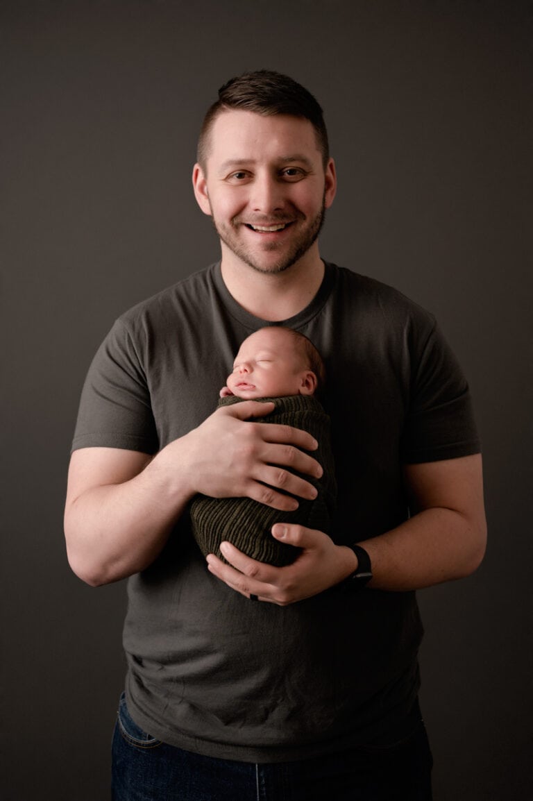 dad holding newborn son with a huge smile