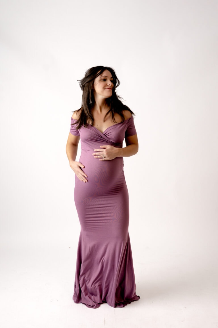 Maternity session in the Morgantown studio. Mom is wearing a purple dress on a white background.