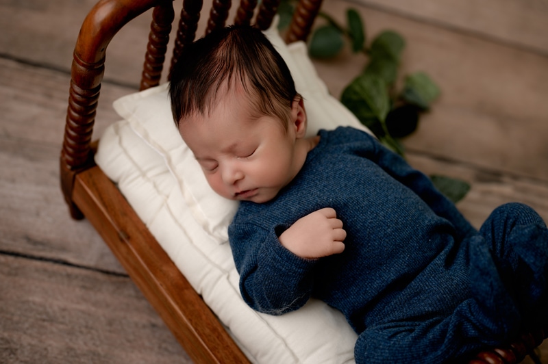 Newborn boy in a bed asleep with greenery