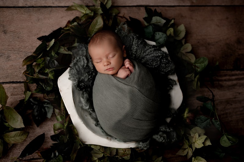 baby boy with greenery in a bowl