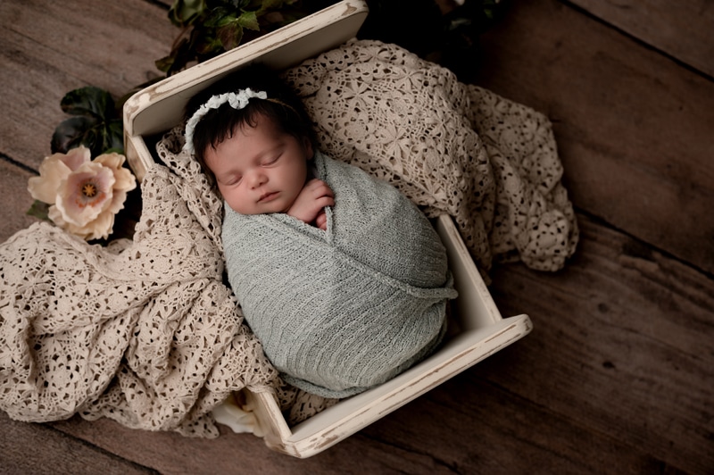 Newborn baby girl in sage green and lace with flowers