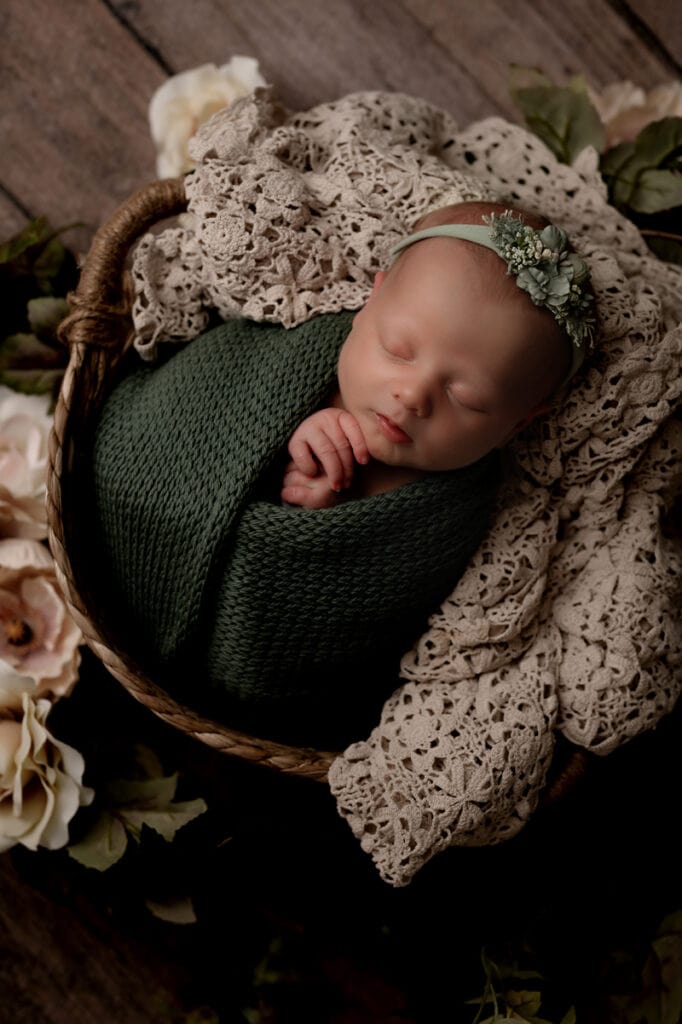Newborn baby girl in a basket with vintage lace