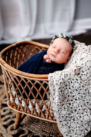 Newborn baby girl in a basket with a flower crown.